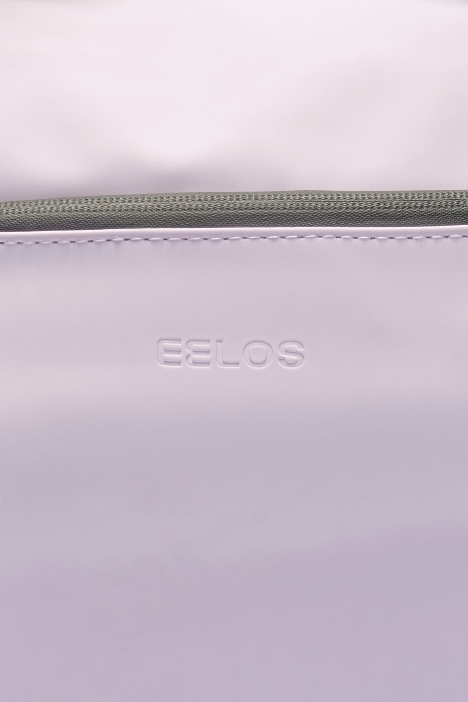 Close-up of a light lavender or pale purple bag with a green zipper and the brand name 'CELOS' debossed on the front.