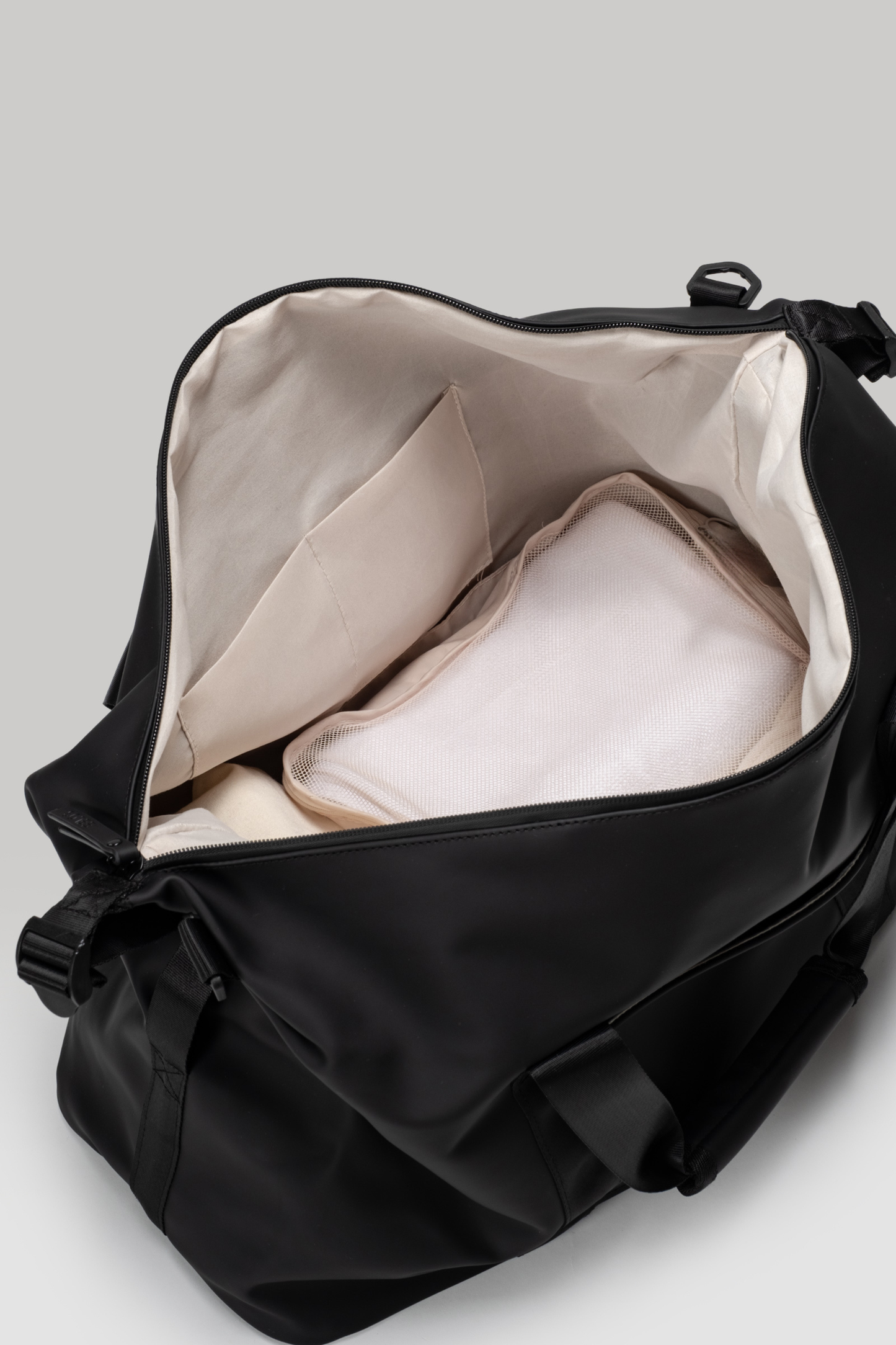 Black duffel bag with beige interior on a light gray background
