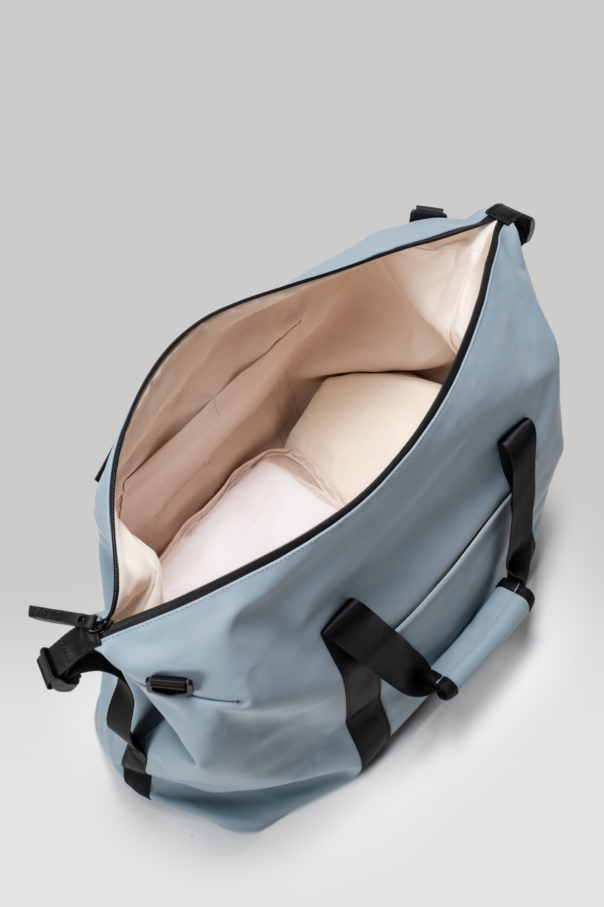 Light blue duffel bag with black straps on a light gray background