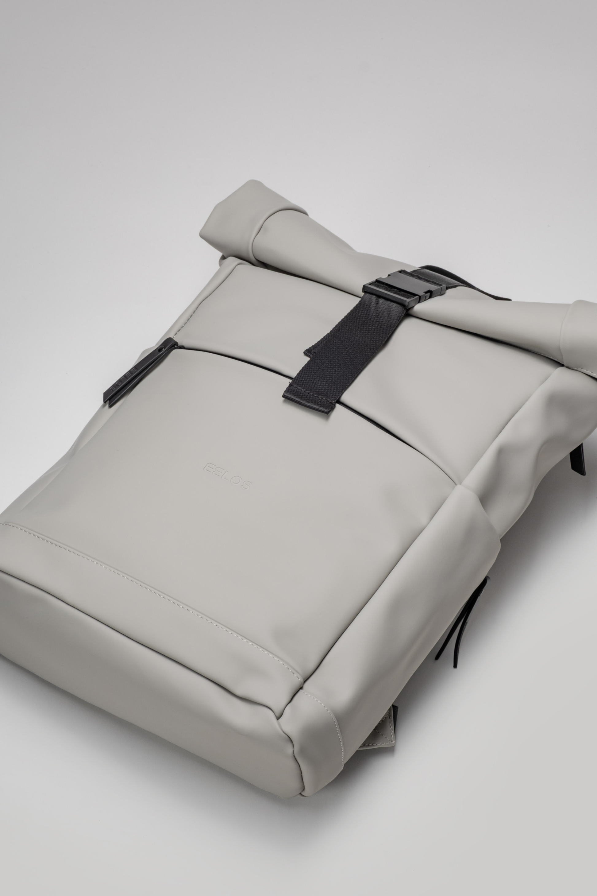 Gray backpack with a black strap on a light gray background