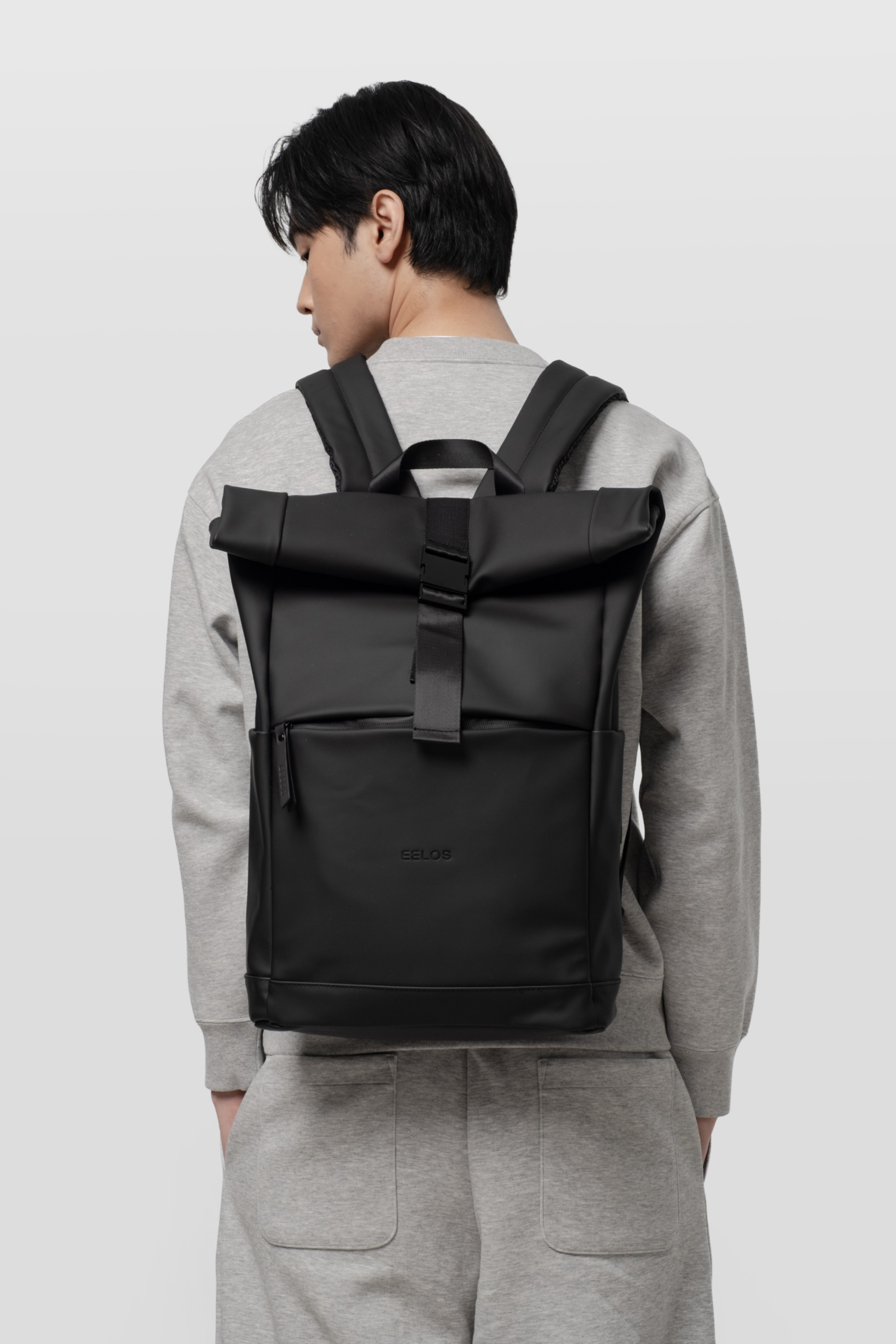 Person wearing a black backpack on a plain background