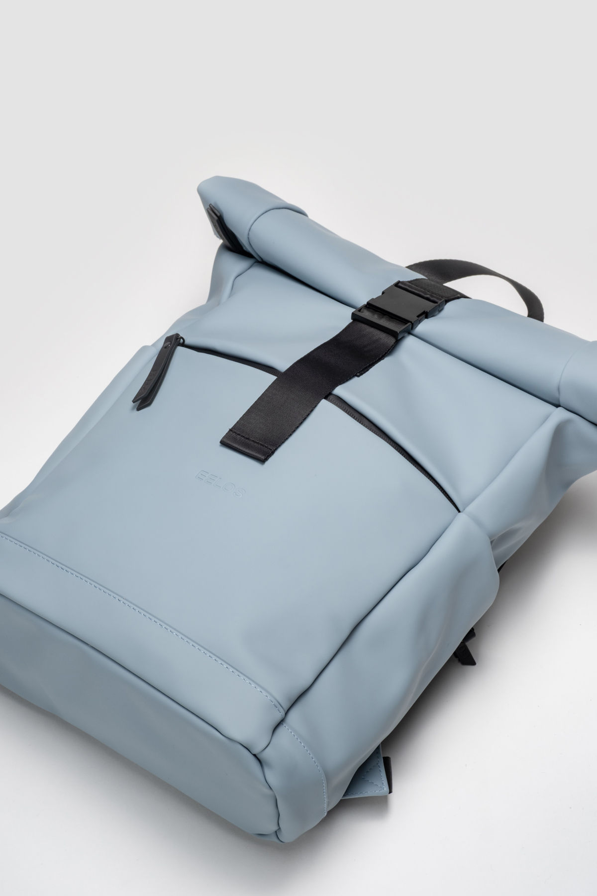 Light blue backpack with black straps on a light gray background