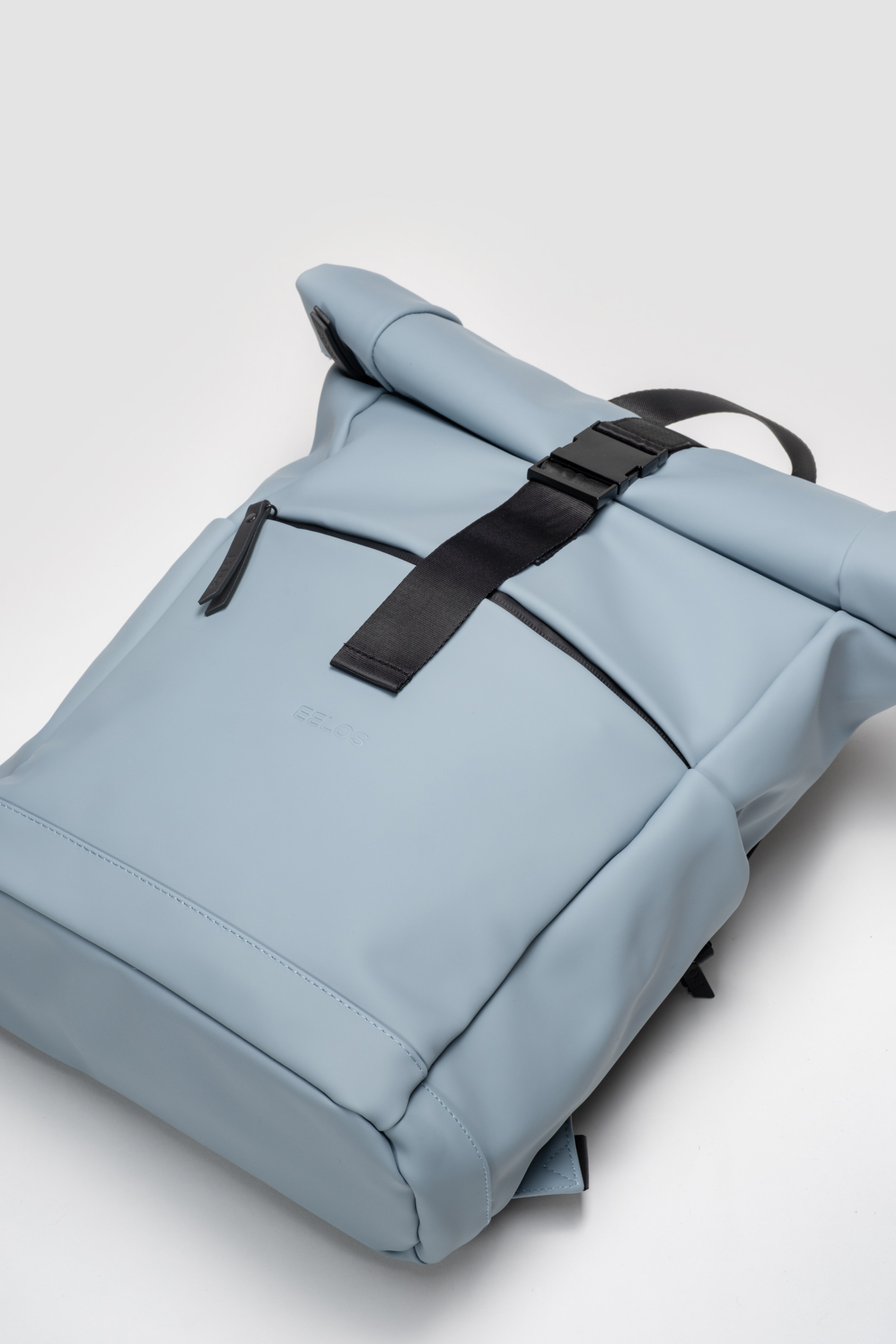 Light blue backpack with black straps on a light gray background
