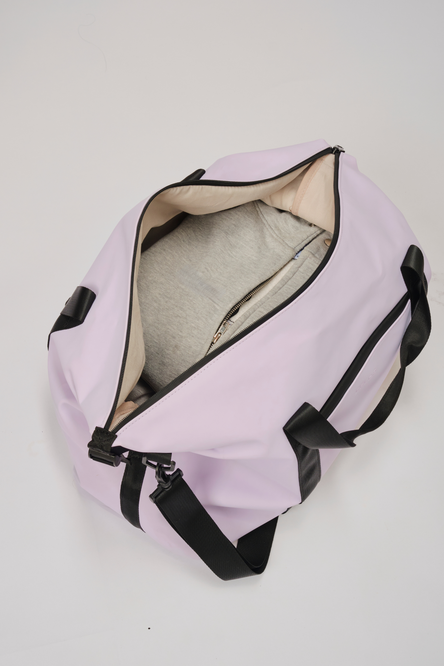 A light purple duffel bag with black handles and trim, shown open with a gray shirt inside, on a light gray background.