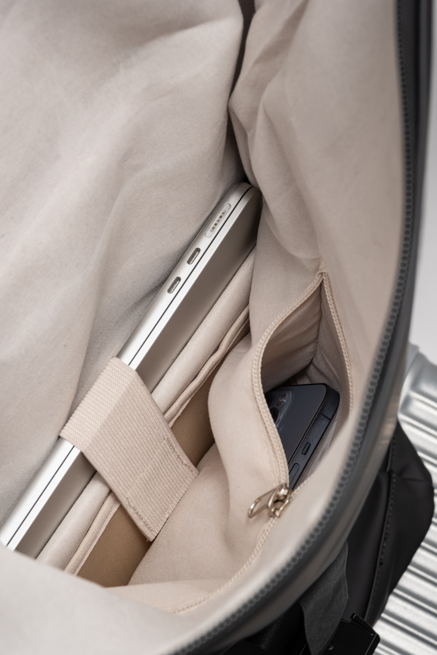Close-up of a beige suitcase interior with a phone and tablet inside.
