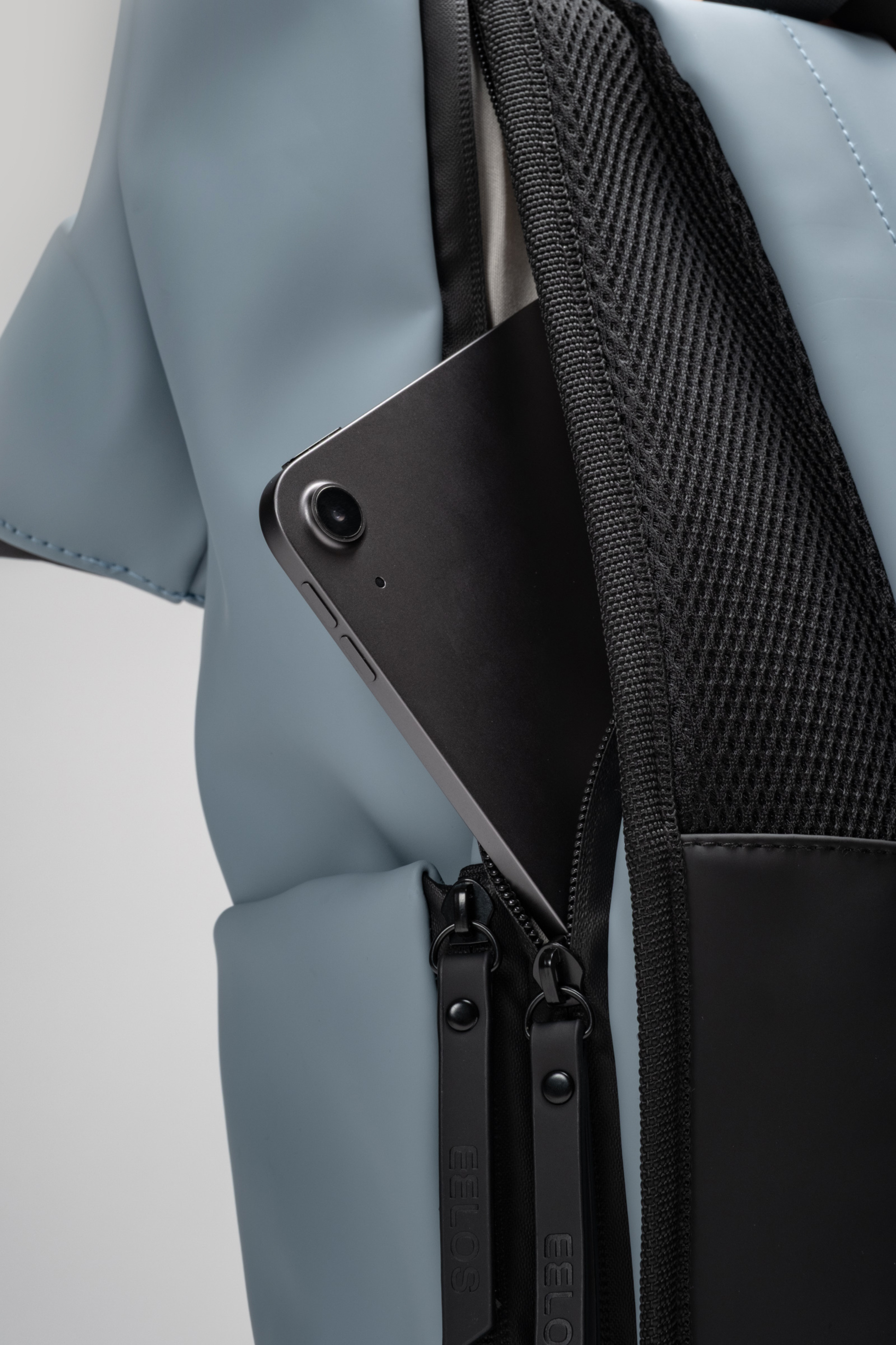 Close-up of a black phone case with a textured back, attached to a light blue jacket pocket.